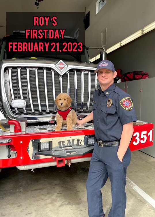 Roy at a fire department presentation with two firefighters and an audience
